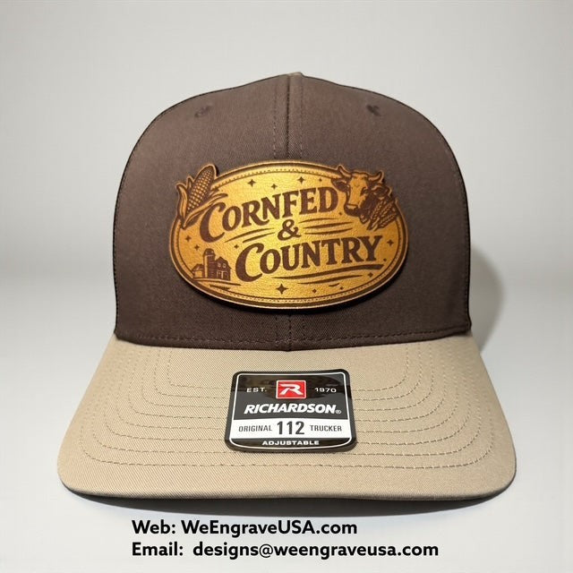 WeEngrave USA brown and tan Richardson 112 trucker hat with engraved leather patch that says "CornFed & Country" with farm imagery.