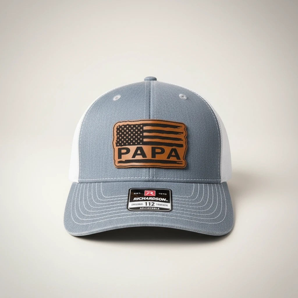 WeEngrave USA grey trucker hat with white mesh back and engraved leatherette patch featuring American flag and PAPA text.